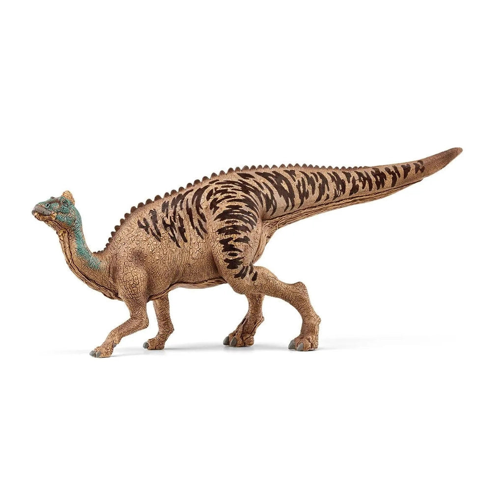 Image of the Edmontosaurus figurine. It is a striped tan and brown dinosaur with a oxidized copper colored head. It has a small tan fin on the top of its head.