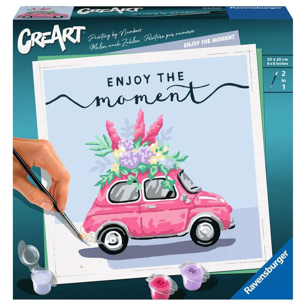 A painting by numbers with a car adorned in flowers. the words enjoy the moment are at the top to remind the painter to relax. the paint brush has two brushes, one on each tip for fine tuning. 