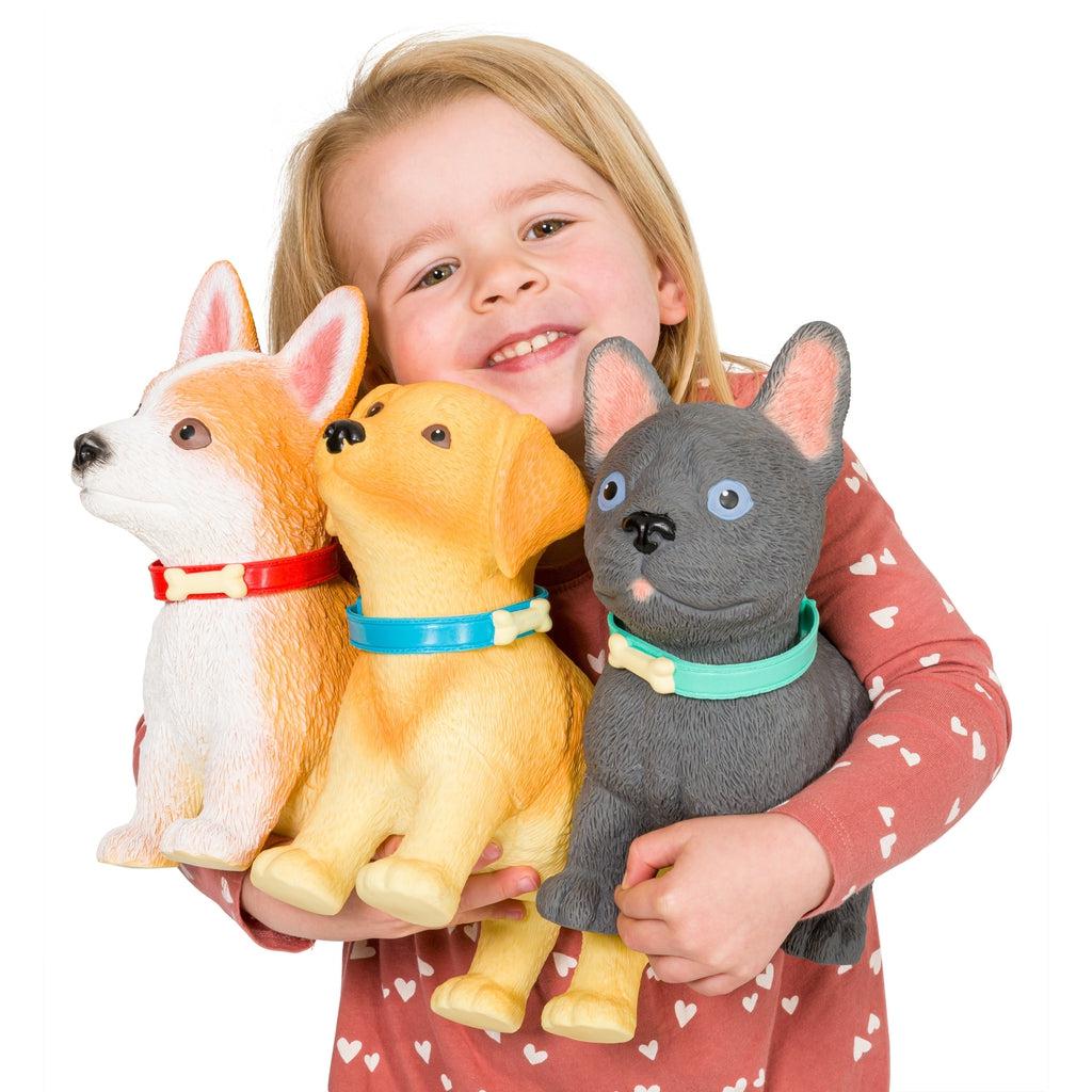 Image of a little girl holding all the possible dog figurines you could recieve. One is a golden retreiver puppy, one is a french bulldog puppy and one is a corgi mix puppy.