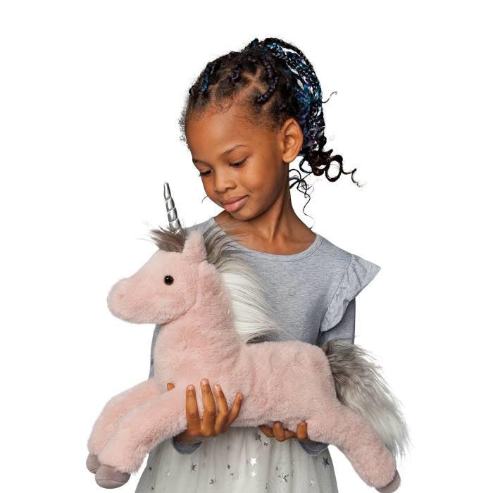 image shows a little gitl holding the unicorn in her hands. the unicorn is about as big as a small child's torso. 