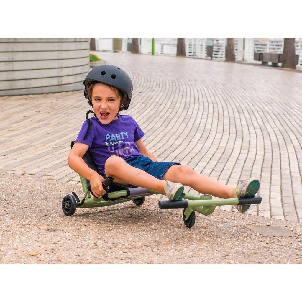 picture of a child using the ezyroller on the street, he is wearing a helmets and smiling while rolling around