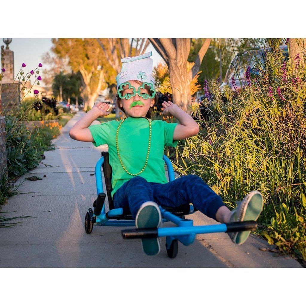a kid is decked out in st.patricks day appearal with 4 leaf clover glasses, green mustache and necklace while rolling down the sidewalk on an ezyroller