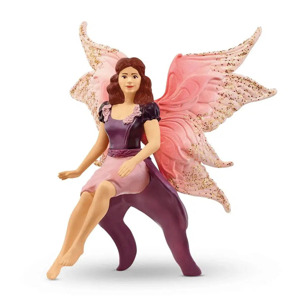 Close up of the fairy figure. It is a brunette fairy with pink glittery wings and a purple dress.