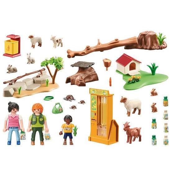 this image shows everything in the zoo, from props to set up a petting zoo and give some nature, to a stand full of animal feed. there is a family, a zookeeper, and animals galore. 