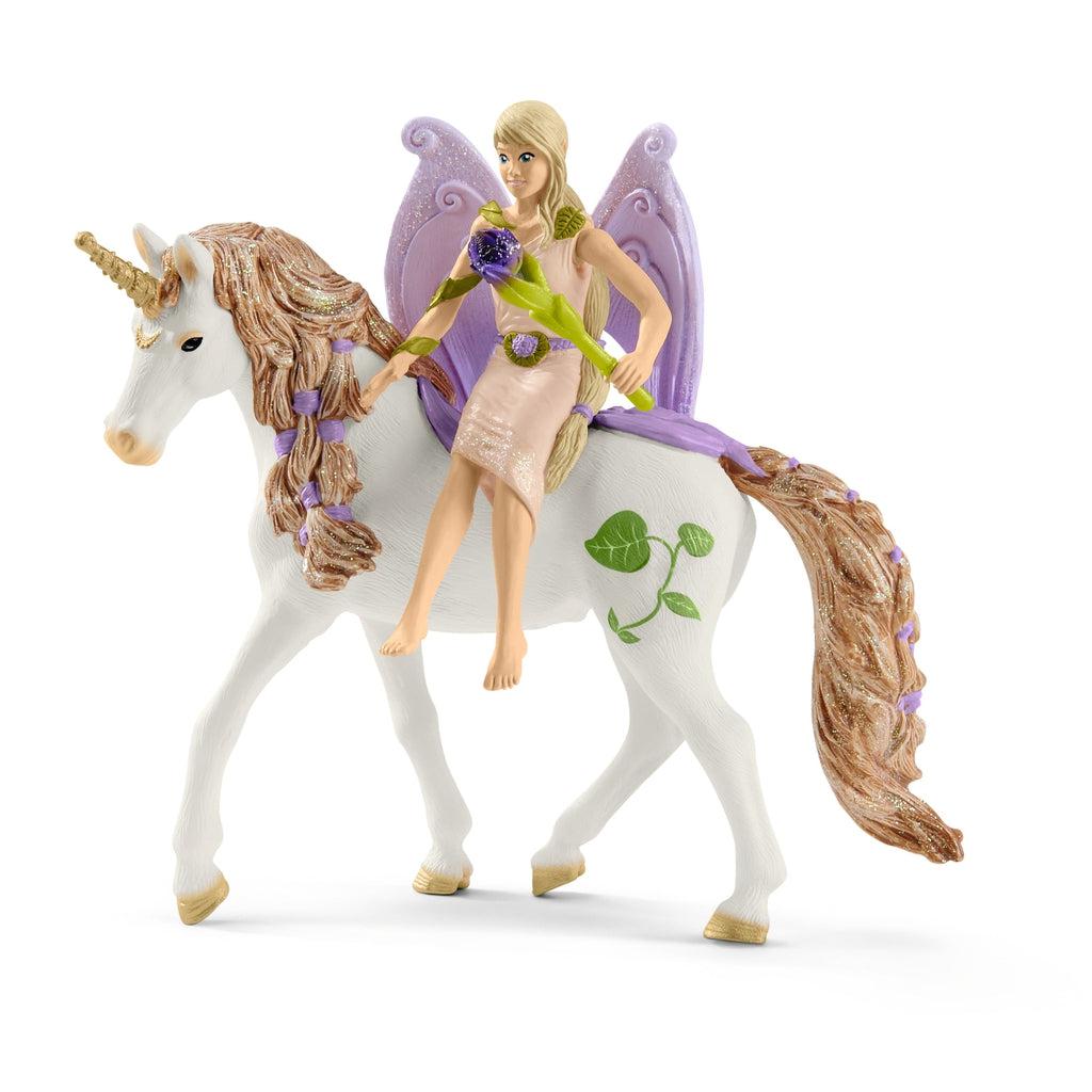 Close up of the fairy riding one of the unicorns. She is wearing a blush dress and her wings are light purple. The unicorn is white with a golden mane and horn.
