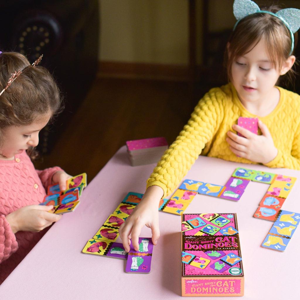 this image shows two kids playing dominoes, the cards are big, so they fit in the entire hand, and can not be easily choked on. 