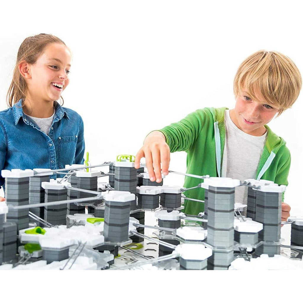 Two kids are building their own GraviTrax set. They have smiles on their faces though they are concentrating.