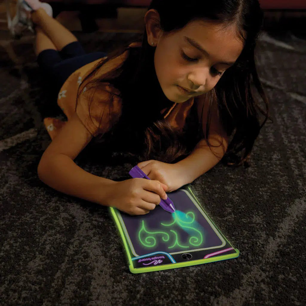image shows a child doodling with a glow in the dark boogie board