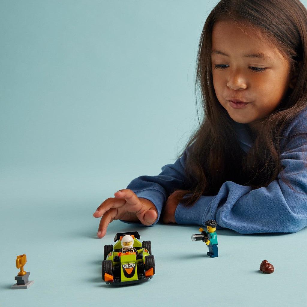 image shows a girl playing with the LEGO race car