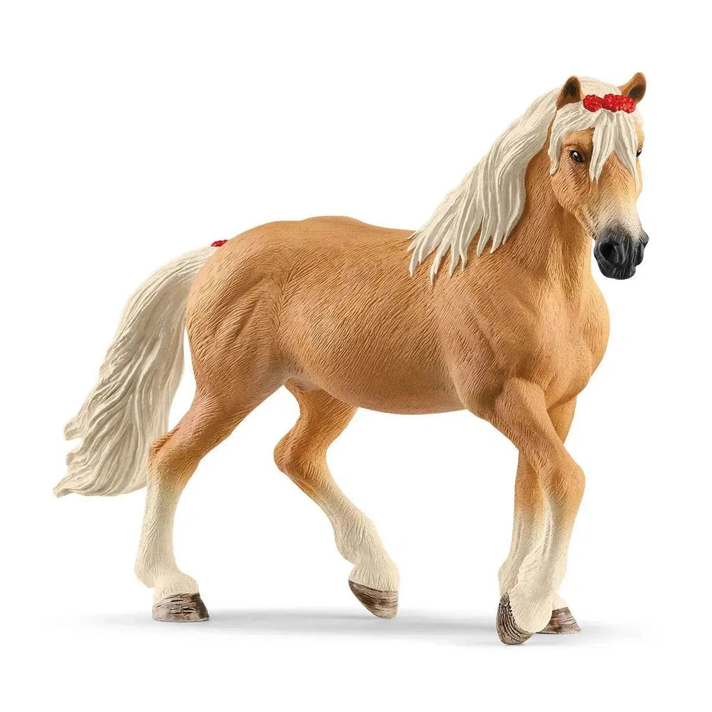 Image of the Halfinger Mare figurine. It is a honey brown horse with light white mane and tail. She has red flowers in her hair and at the base of her tail.