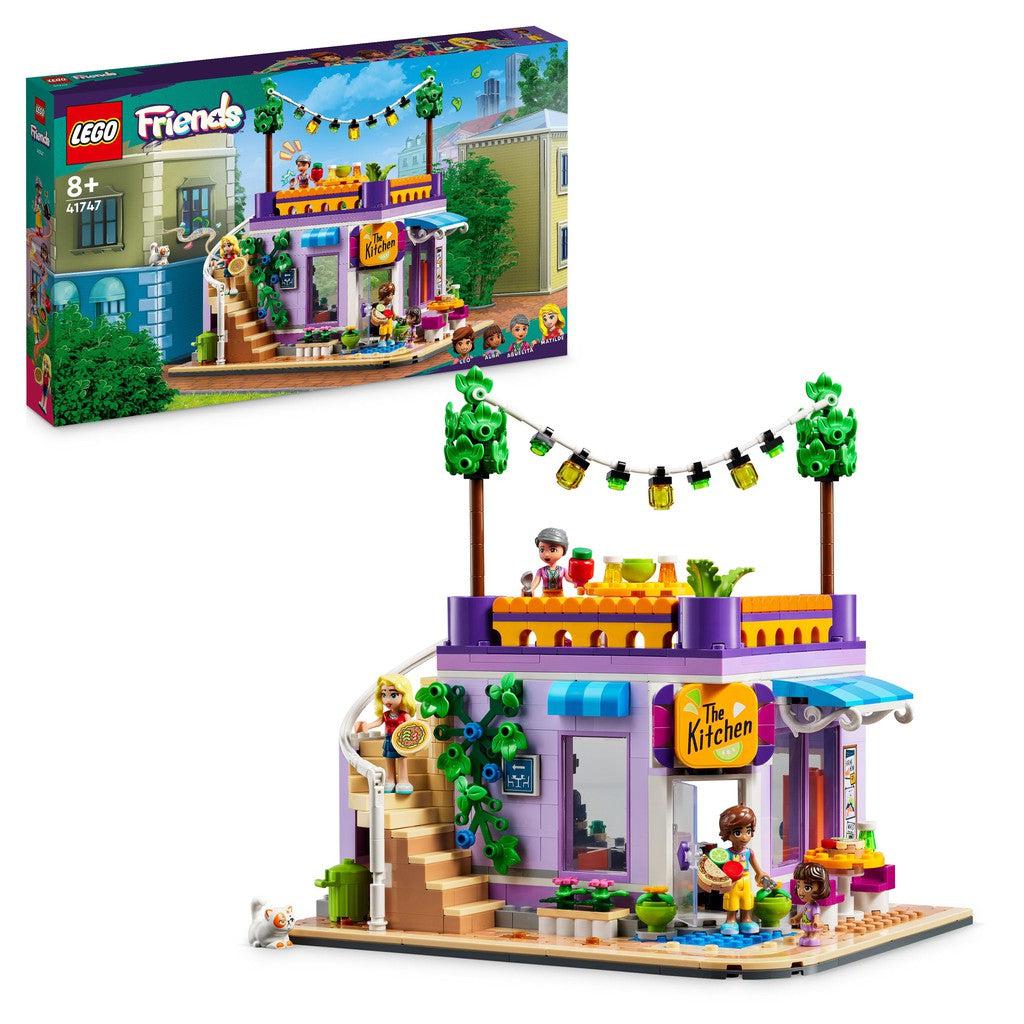 image shows the LEGO Friends community kitchen. There are plants along the outside and a roof on the kitchen with stairs that lead up. 