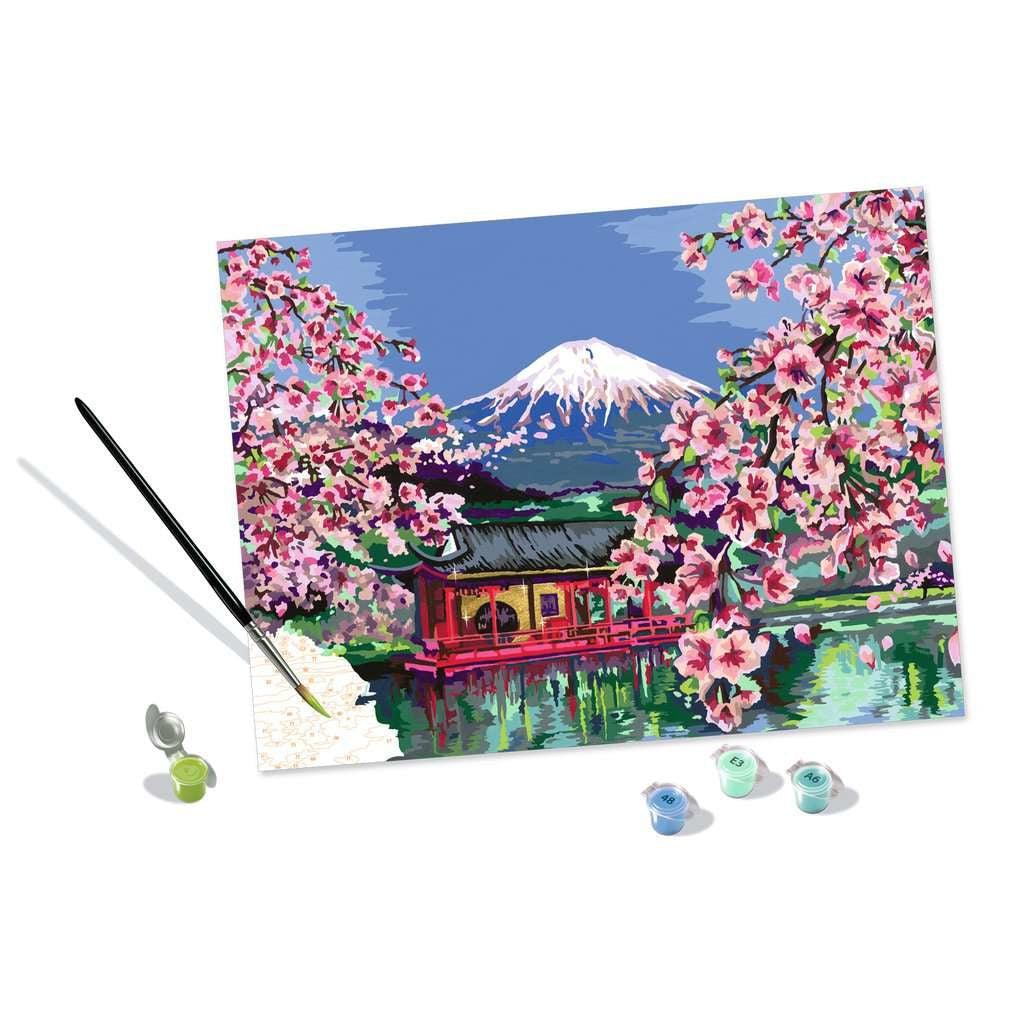 This picture shows a paint brush adding some green buds to a cherry blossom tree, showing off the many numbers to bring this painting to life. 