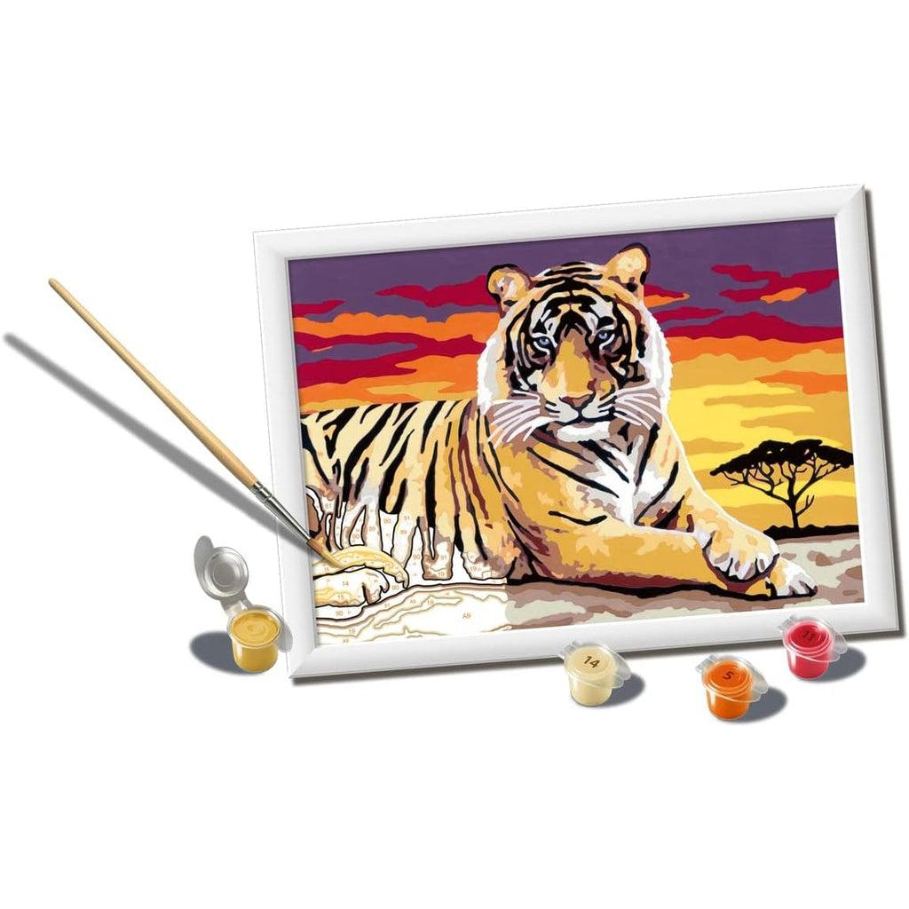 this picture shows a paint brush adding a dash of orange to the tigers paws as he calmly waits. the numbers can be seen in this image to follow the paint by numbers kit.