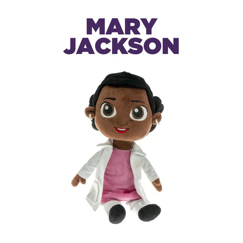 A doll of mary jackson, NASA's first african american female engineer. The doll is wearing a pink shirt, a white labcoat, and white pants.