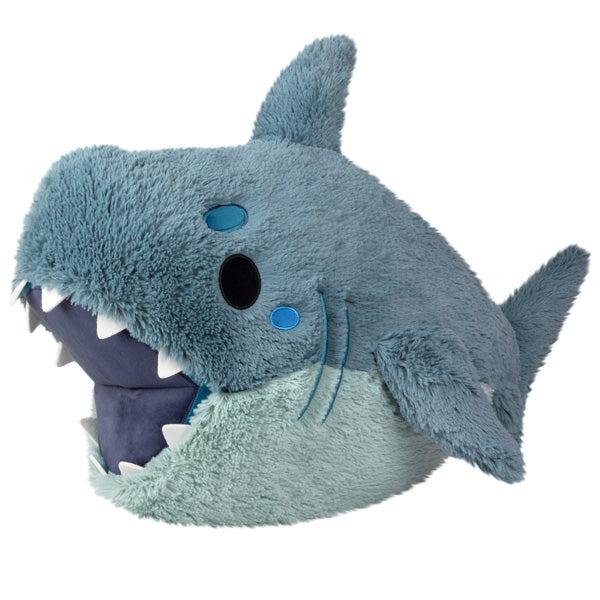 Plush toy shaped like a cartoonish Megalodon, featuring a big smile, protruding teeth, and large, round blue eyes.