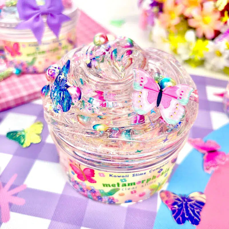 Image of the open slime. Because of the pearl bead add-ins, the clear slime looks like it is rainbow colored. It also comes with different colored butterfly charms.