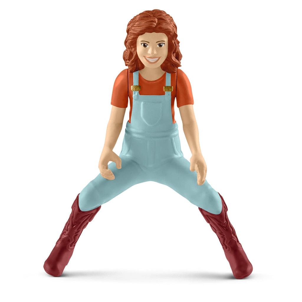 Close up of the Mia figure. She is wearing a red shirt to match her red hair and light blue overalls. She is made so that she is constantly in a sitting/riding position with her legs spread apart.