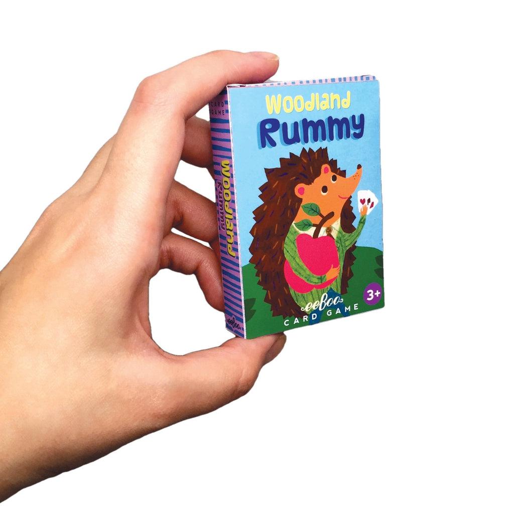 Woodland Rummy is on display. the cards are small and fit on the palm of a hand. a colorful hedgehog is holding up a sex of cards on the box. 