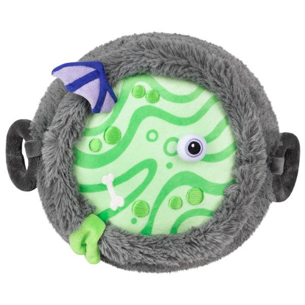 Top view of the plush. The green goo has ripples and emboridered green bubbles. It also has an eyeball, a bone, and a wing sticking out.