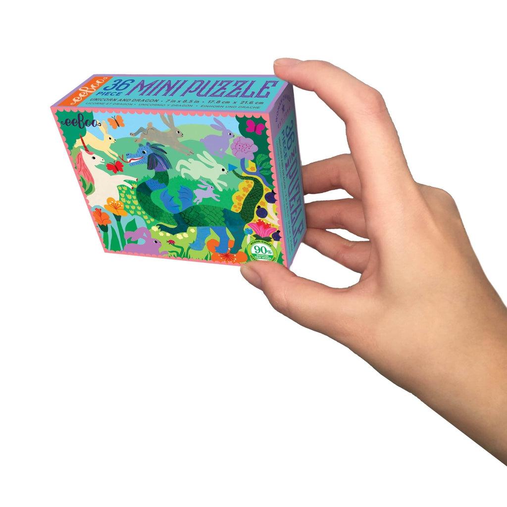 this image shows a hand holding up the mini puzzle. the small box holds 36 pieces and an image of a dragon and unicorn on the box