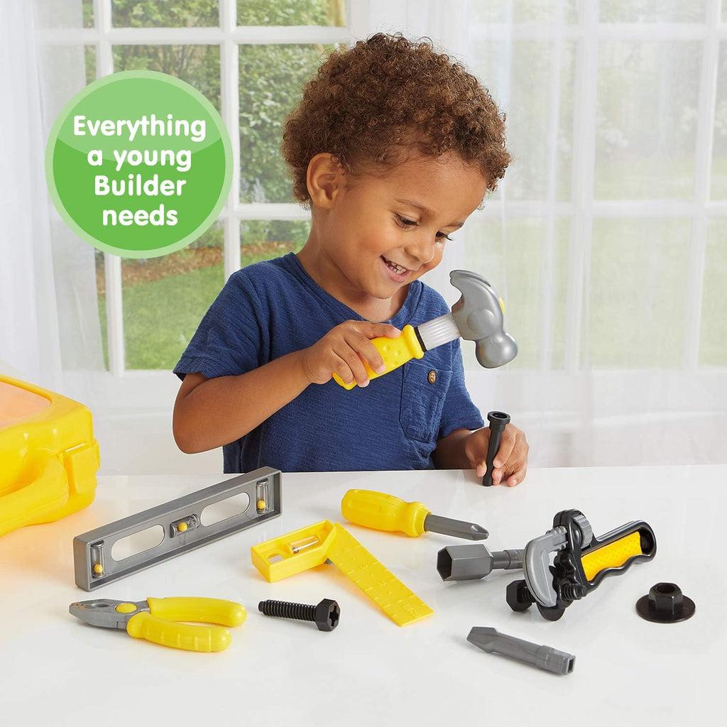 A young boy using the hammer on the fake nail to happily pretend to sco DIY work