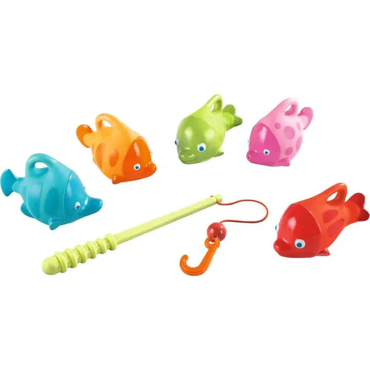 Image of all the parts of the toy outside of the packaging. The toy includes a fishing rod and five fish in different colors: blue, orange, green, pink, and red. Each fish has a hook on its back so it can be picked up by the fishing rod.