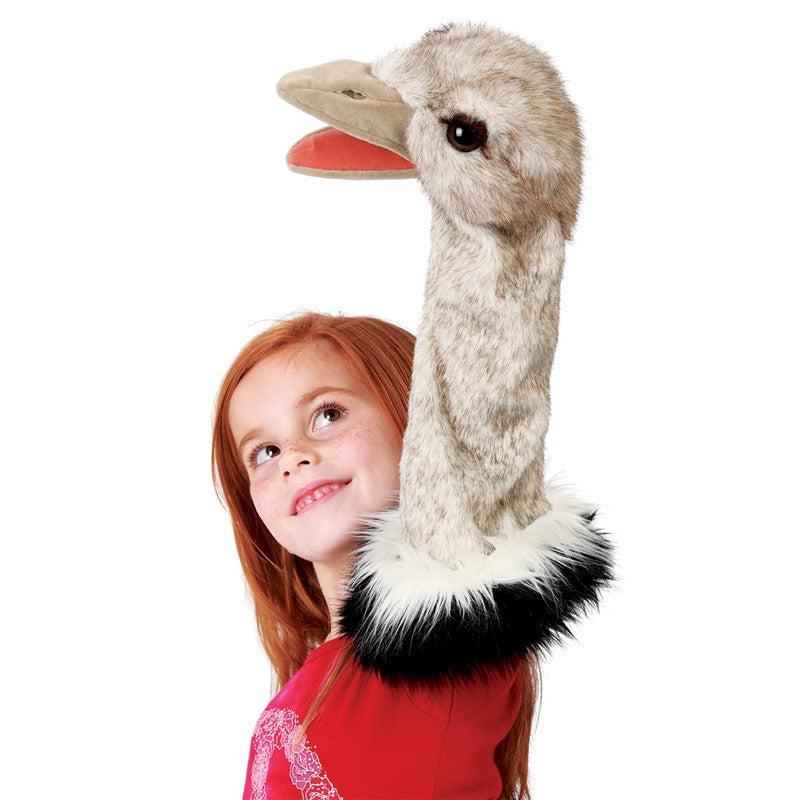 Young girl plays with ostrich puppet on hand and arm.