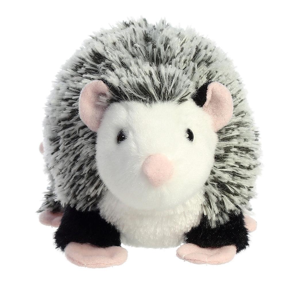 Image of the Ozzie Opossum plush. He has a feathered grey back with black legs, a white belly, and pink nose, ears, feet, and tail.