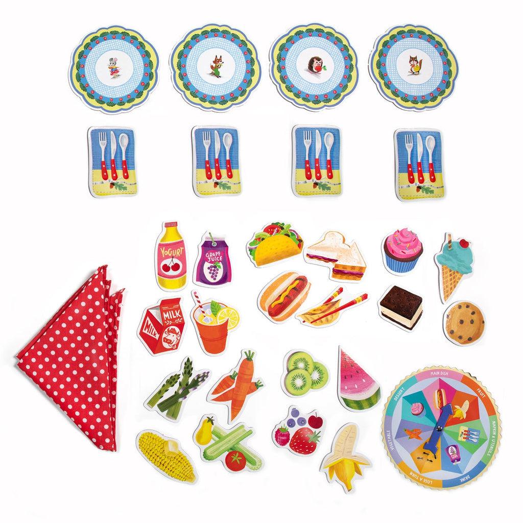 this image shows everything in the box. a tablecloth, 4 plates and silverware, an assortment of food cards, and a spinner. 
