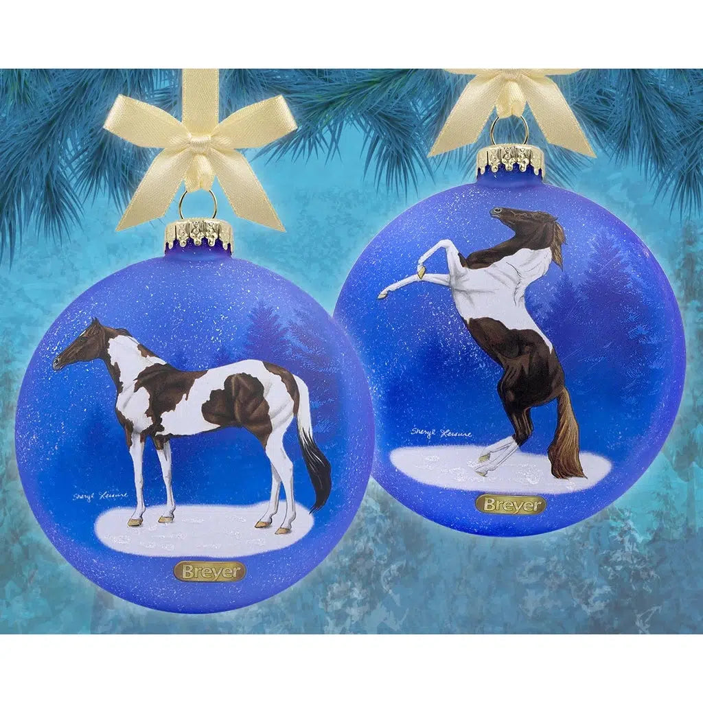 Image of the two Pinto Artist Signature Ornaments up against a blue Chirstmasy background. Ornaments described on next images.