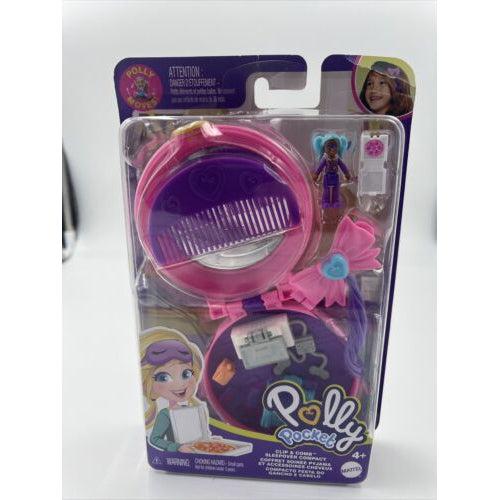 Image of the packaging for the Polly Pocket Micro Clip & Comb Sleepover Compact play set. The front is made of clear plastic so you can see the included pieces inside.