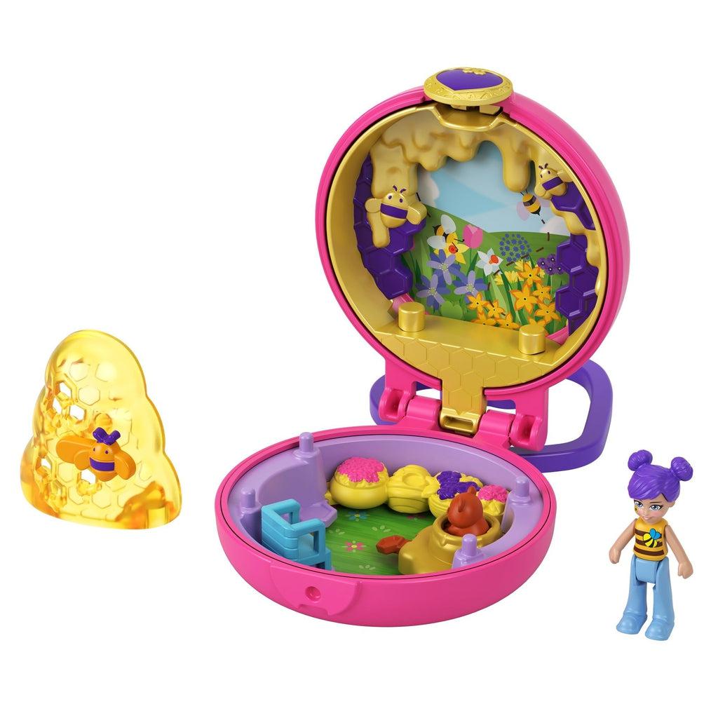 Image of the bee themed Tiny Compact. It comes with a Polly Pocket with a bee shirt, a honeycomb with a bee on it, and a chair. On the inside there is a meadow and a set of bee hives with a bear coming out of one.