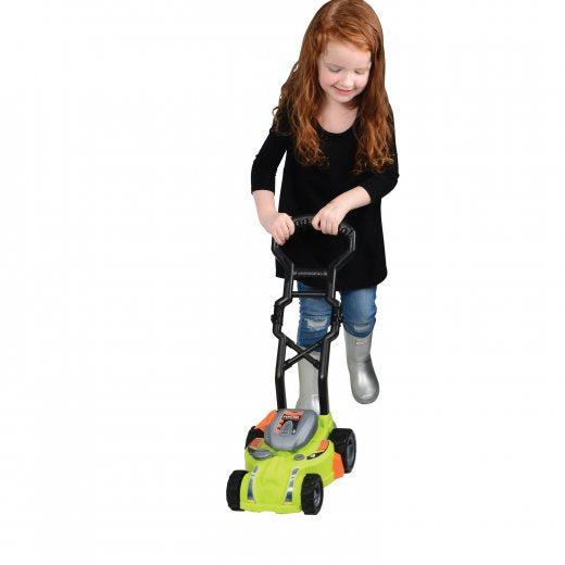 image shows a young girl pretending to mow the lawn