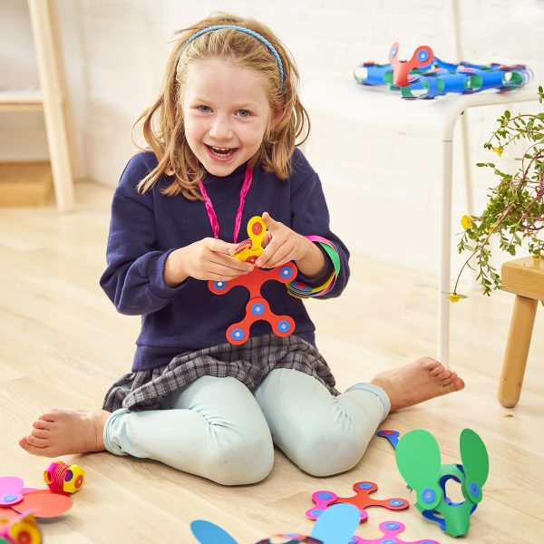 a girl is playing with colorful Clixo magnetic shapes
