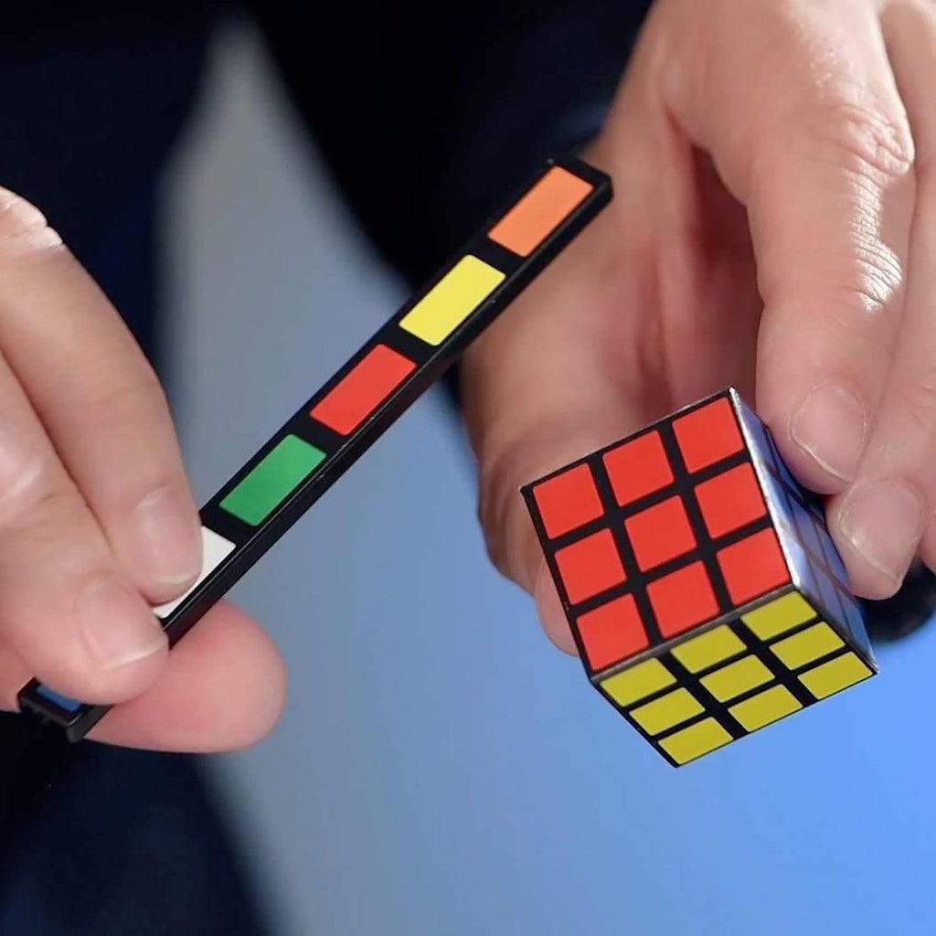 this image shows a rubik's cube and a trange wand with the cute color pallet on it in a magicians hands