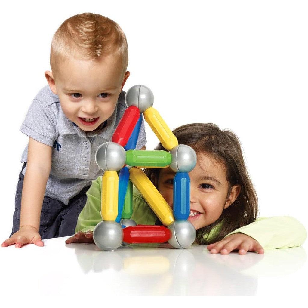 this image shows two kids learning with large magnets and joints as they stick together to make a structure that looks like a house