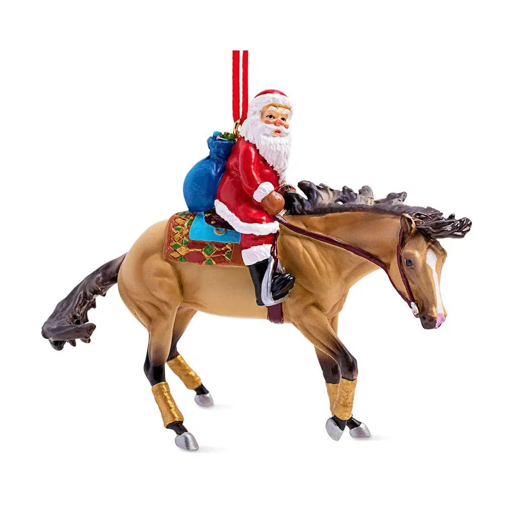 Santa is riding on a light and dark brown bronco. He is wearing his traditional Santa outfit and hat and is carrying a blue bag of toys on his back
