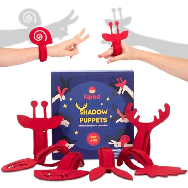 A set of red felt shadow puppets with various animal shapes, displayed in front of a blue box labeled "Shadow Puppets" by Kipod. Two hands wearing the puppets create shadows on the wall, perfect for a shadow puppet show or as playful felt wristbands for Theater enthusiasts.