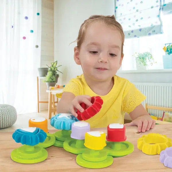 Scene of a little kid playing with the toy by placing the correctly colored and shaped gear covers onto the corresponding gear center.