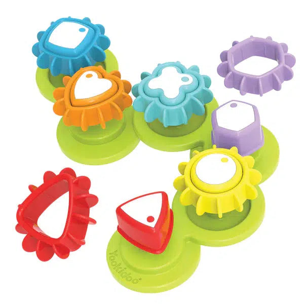 Image of the Shape n' Spin Gear Sorter toy. It is a base with multiple different colored and shaped gear centers that you can attach matching gear covers to. They are red triangle, yellow circle, purple hexagon, light blue plus sign, orange heart, and dark blue square. When they are all attached, moving only one of the gears will move all of them in a chain effect.