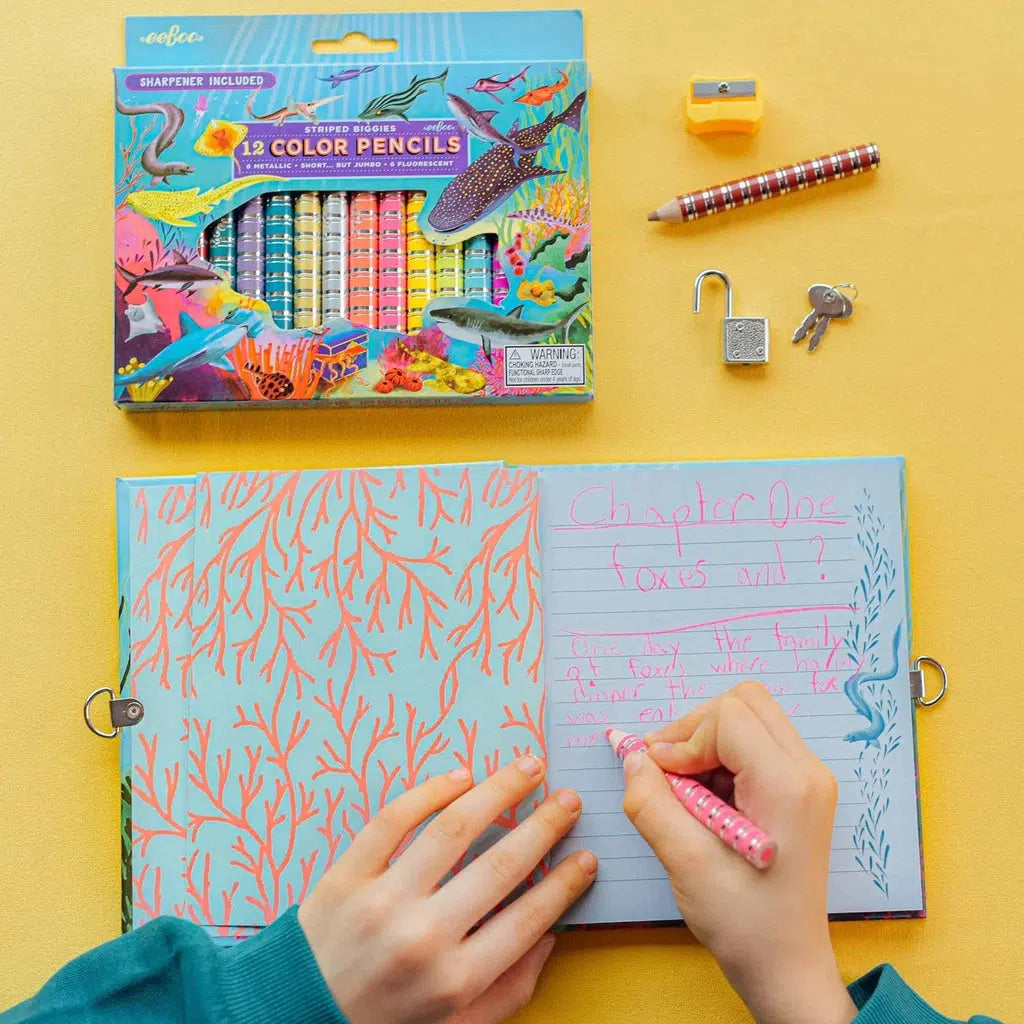 a child is crawing with the colored pencil in a notebook, the pencil look srather large in a childs hand
