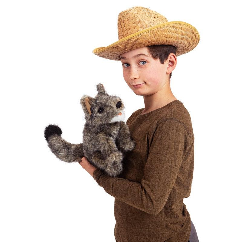 Young boy wearing a cowboy hat holds coyote puppet on hand.