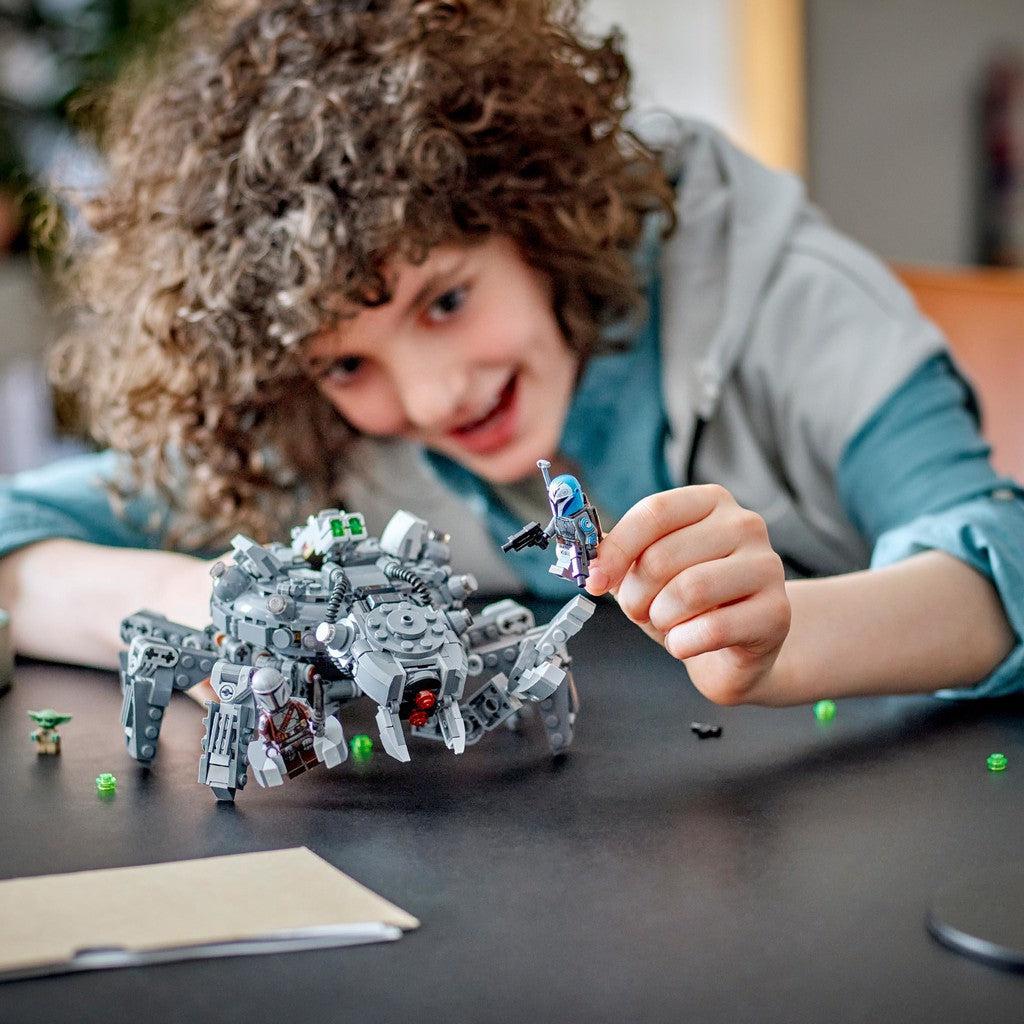 image shows a kid playing with the tank and a Star Wars minifigure