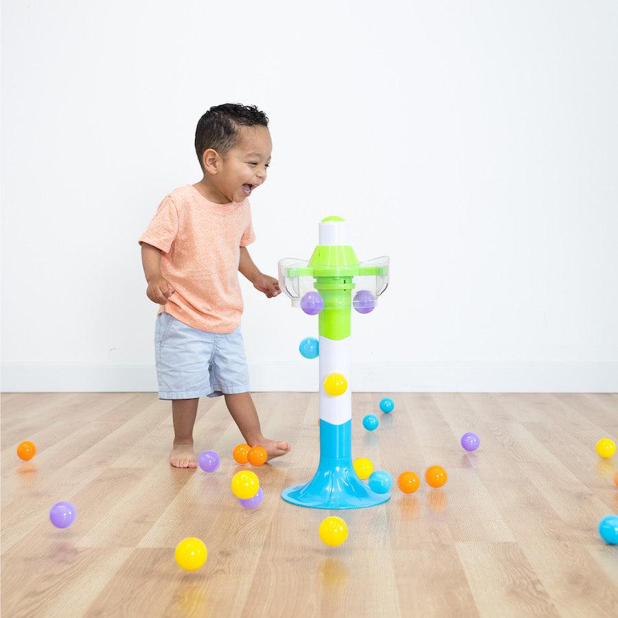 this image shows a child laughing with glee as the balls spill out of the tower and scatter across the floor! now he needs to clean them up