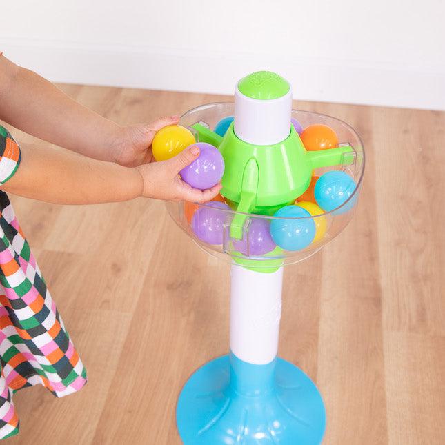 this image shows teh ball being held in the tower, a child carefully putting them all in. there is a button on the top to let them drop