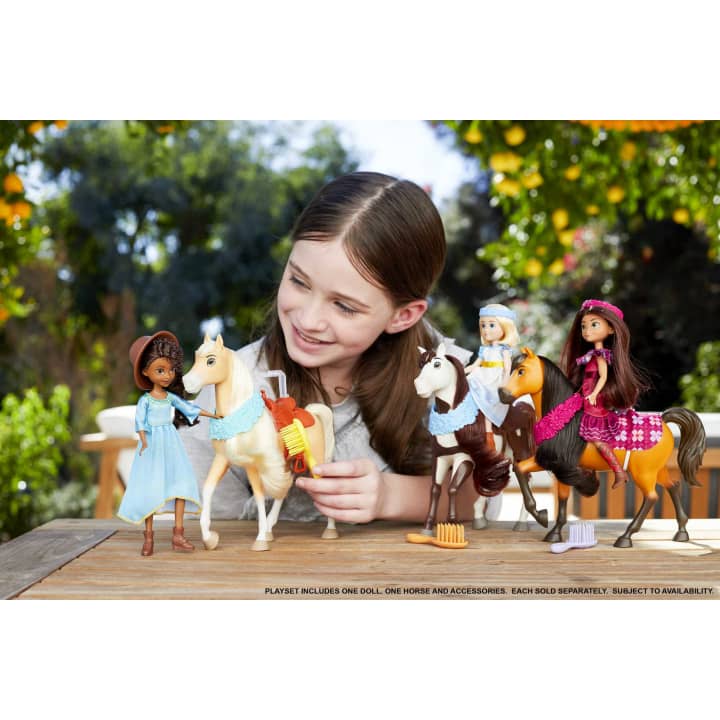 Scene of a little girl playing with the horse and girl dolls while smiling.