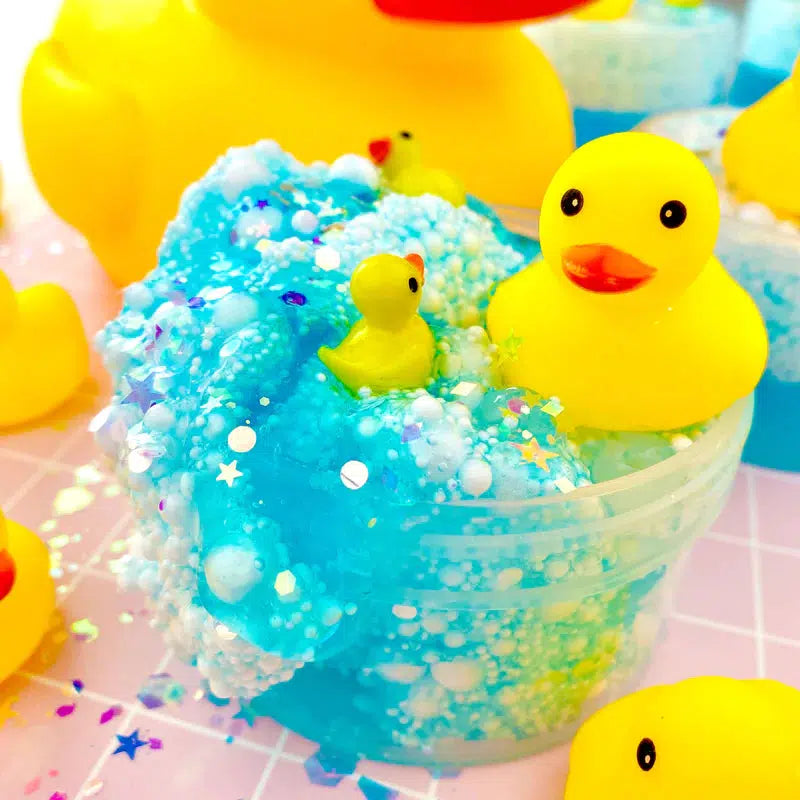 Image of the open slime. It is a azure blue slime full of tons of white foam balls! It comes with glitter add-ins and three duck charms (one large and two small).