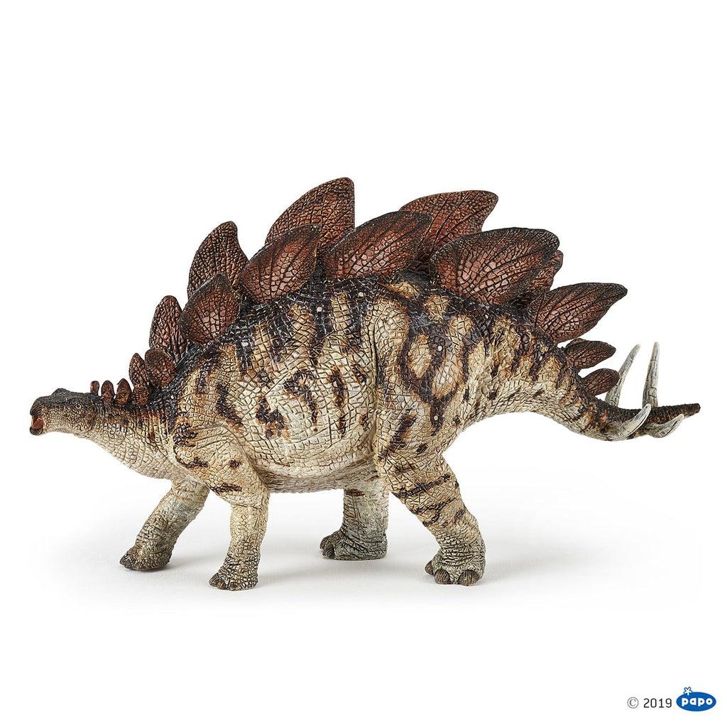 Image of the Stegosaurus figurine. It is a long backed tan dinosaur with large red finned spikes on its back. It has a smalll head and tail.