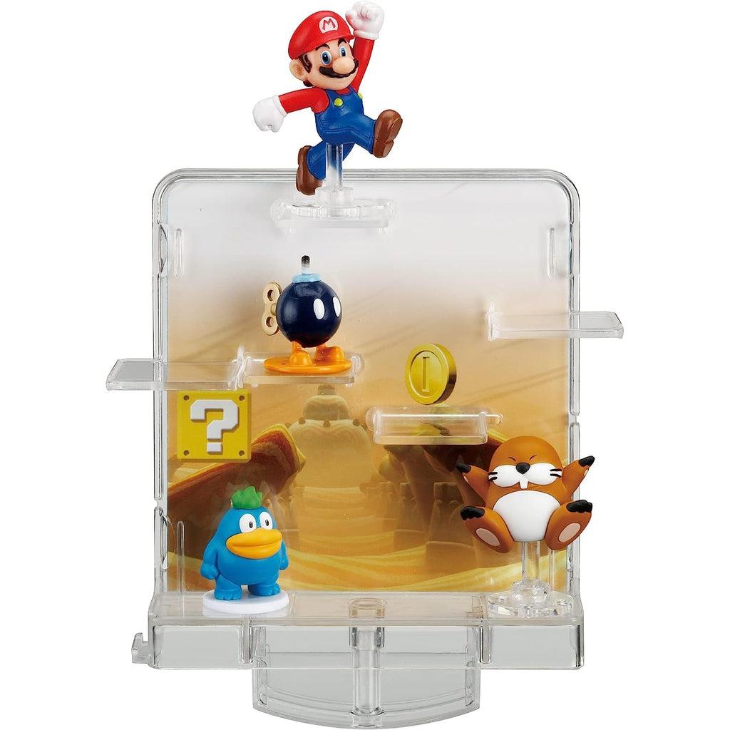Image of the toy outside of the packaging. It is made from clear plastic and it has a desert landscape picture as a background. It comes with a Mario, a bob-omb, a spike, and a monty mole figurine.
