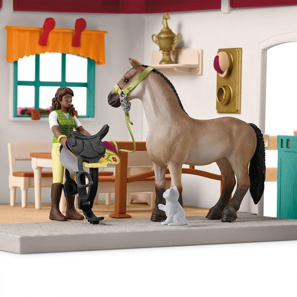 girl figurine is posed holding the saddle next to the horse and cat figures inside the building